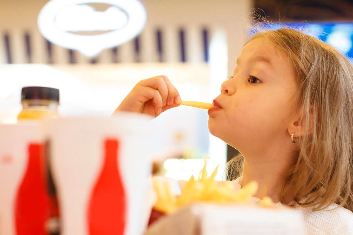 young blonde girl eating fries