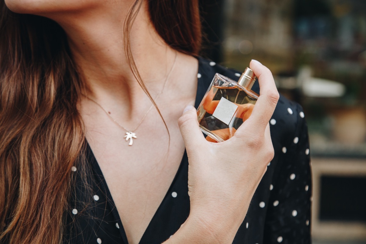 woman holding a perfume bottle and spraying it