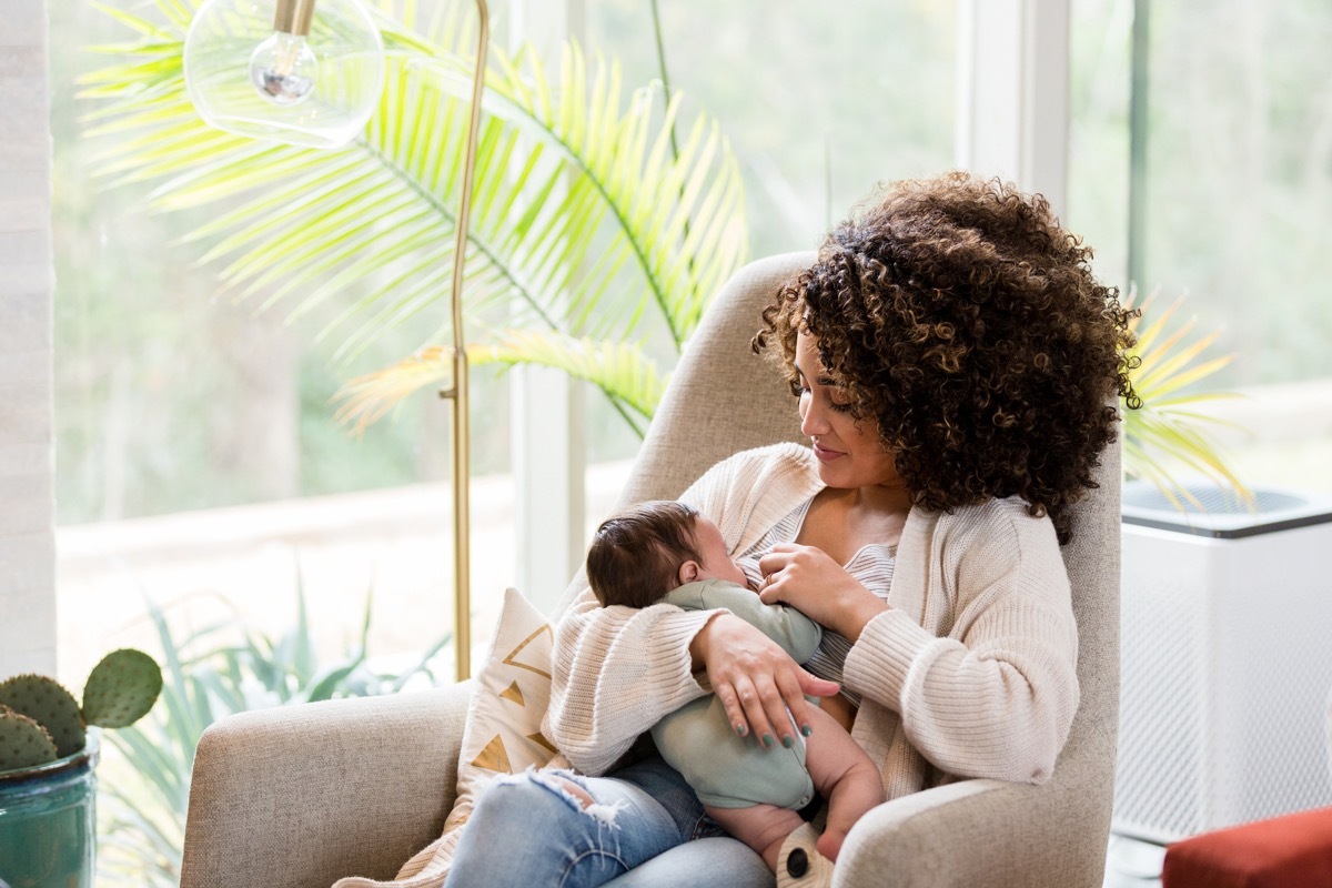 Young mom nurses her newborn baby while in the child's nursery.