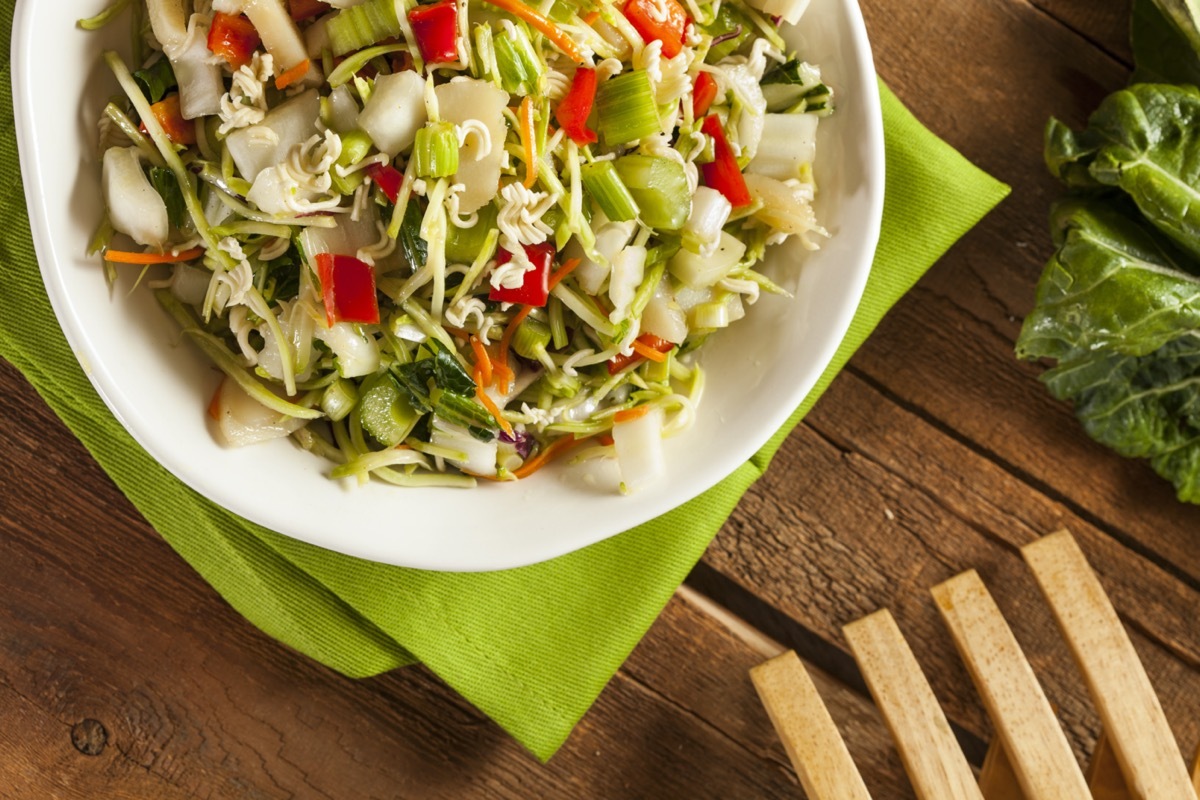 chopped salad in white bowl next to wooden fork