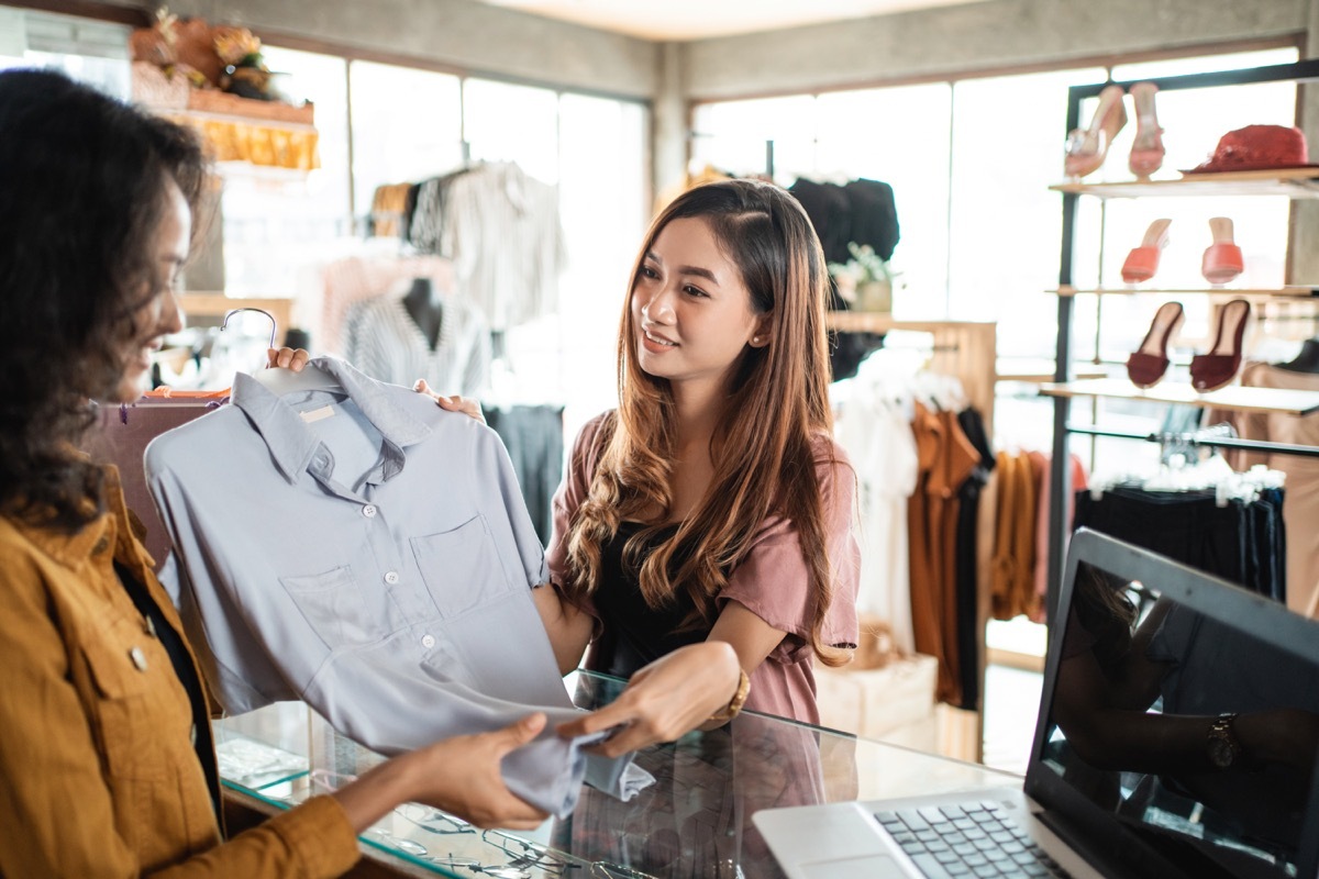 young asian woman returning shirt to store clerk