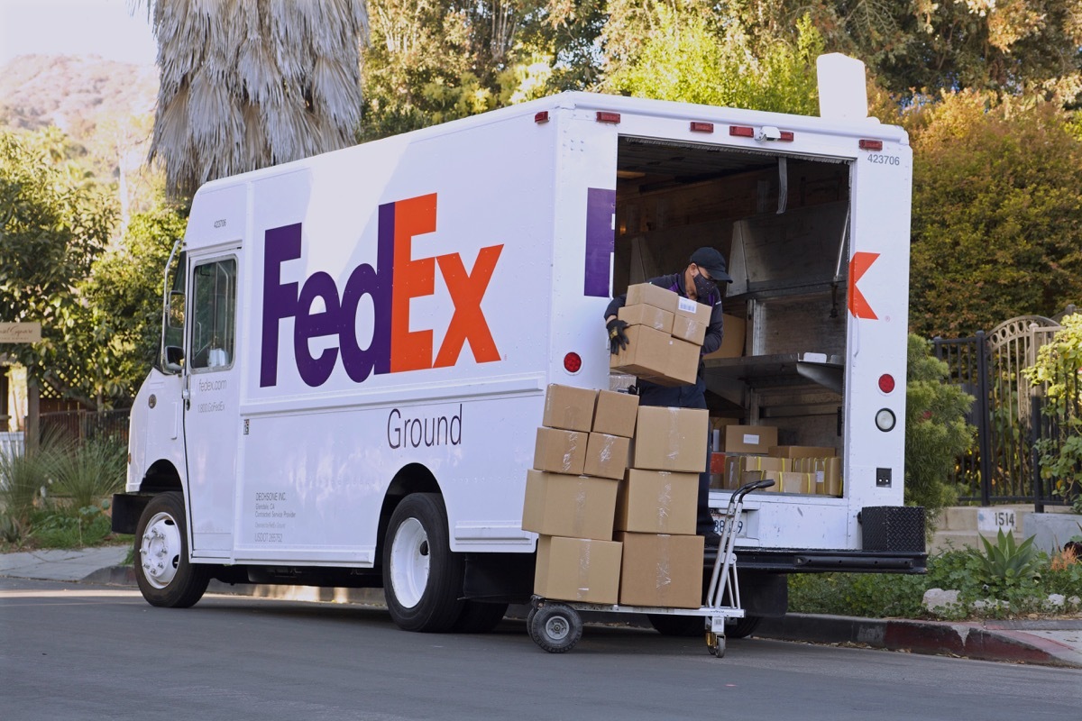 FedEx driver loading boxes into delivery truck day exterior