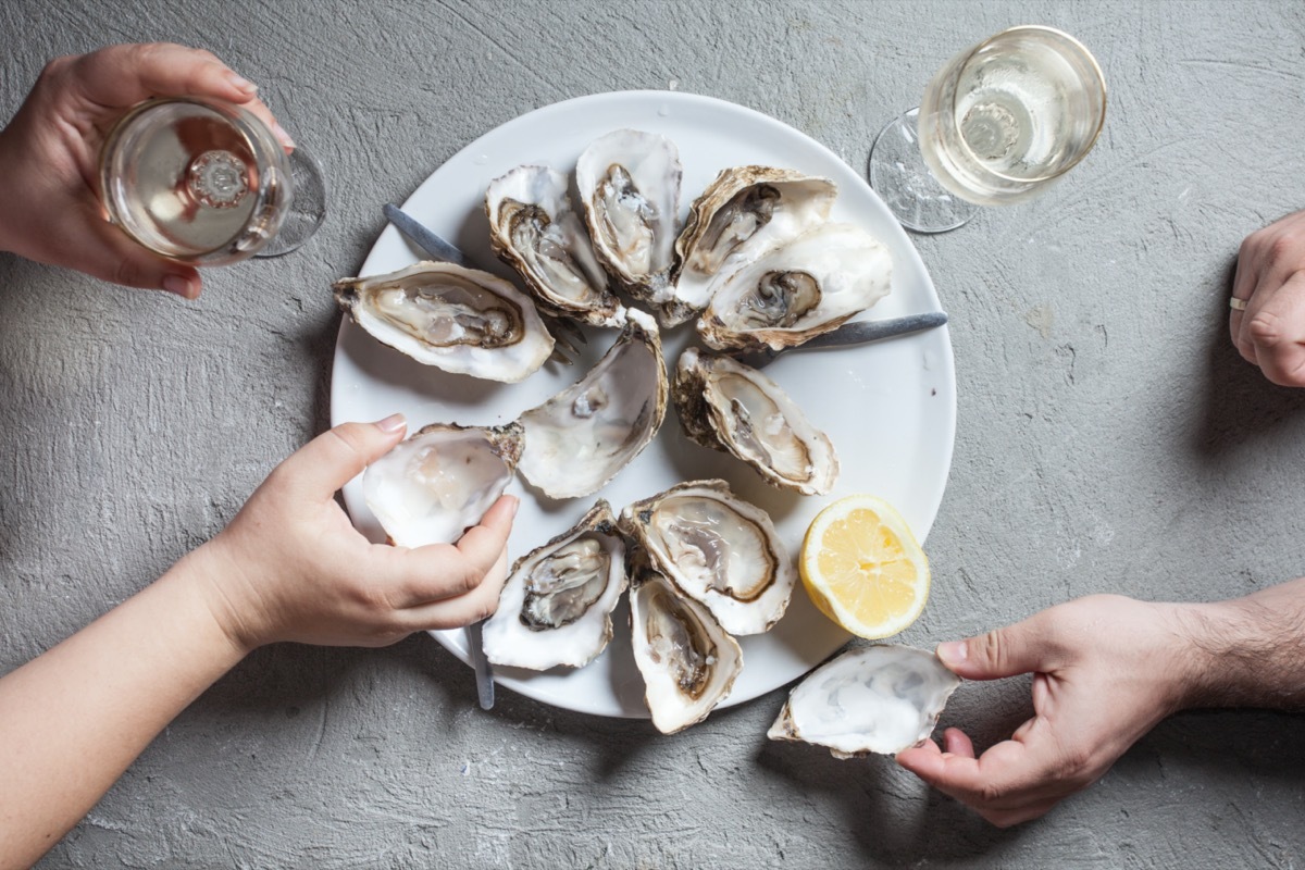 Delicious oysters with slice of lemon and glasses of white wine, top view