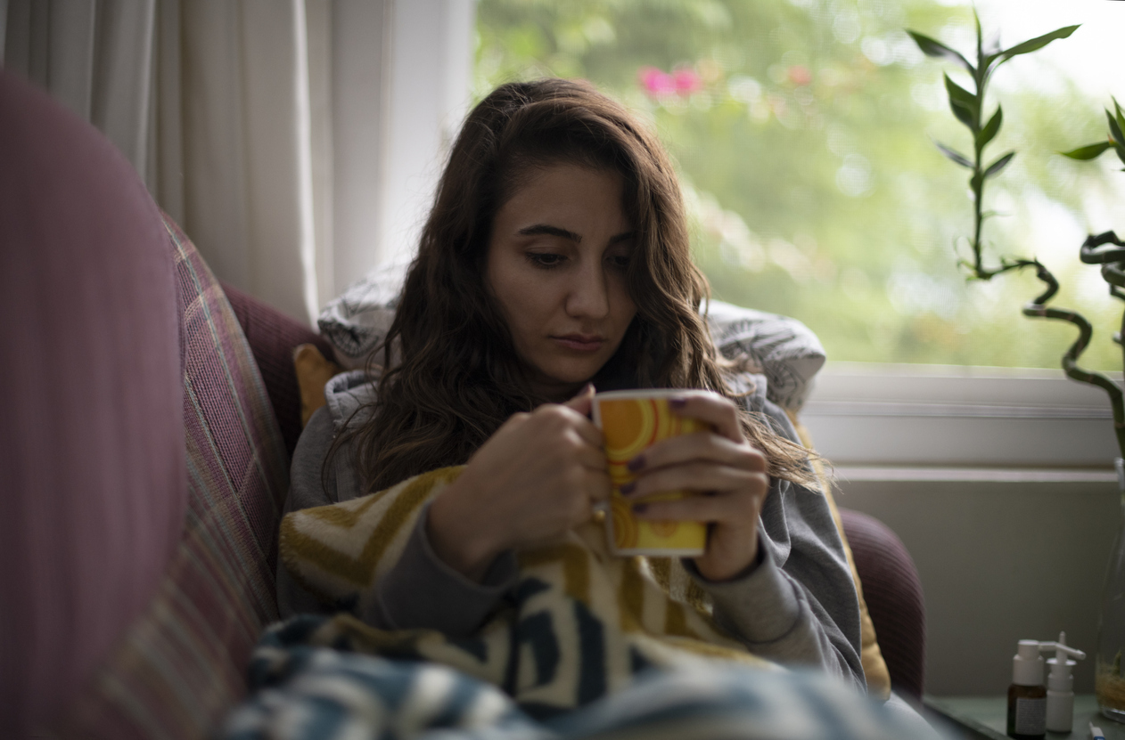 Woman who is feeling sick drinking herbal tea.