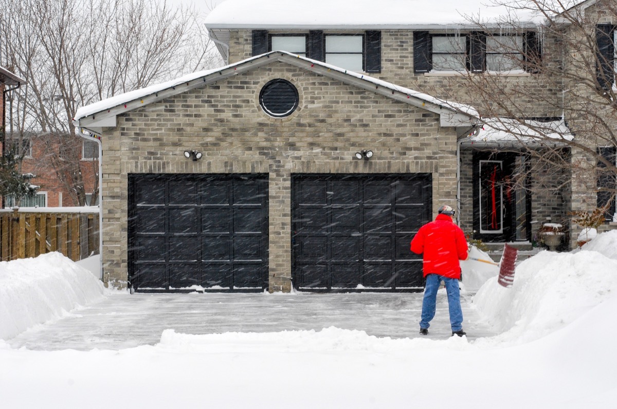 Man Shoveling Outside of the Garage for the Winter {How to Winterize a Home}