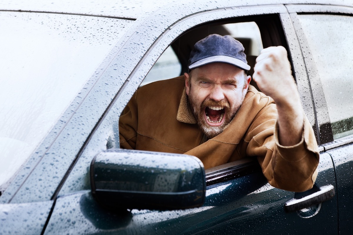 man cursing outside his car window