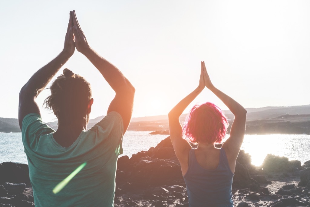 couple doing yoga on a beach