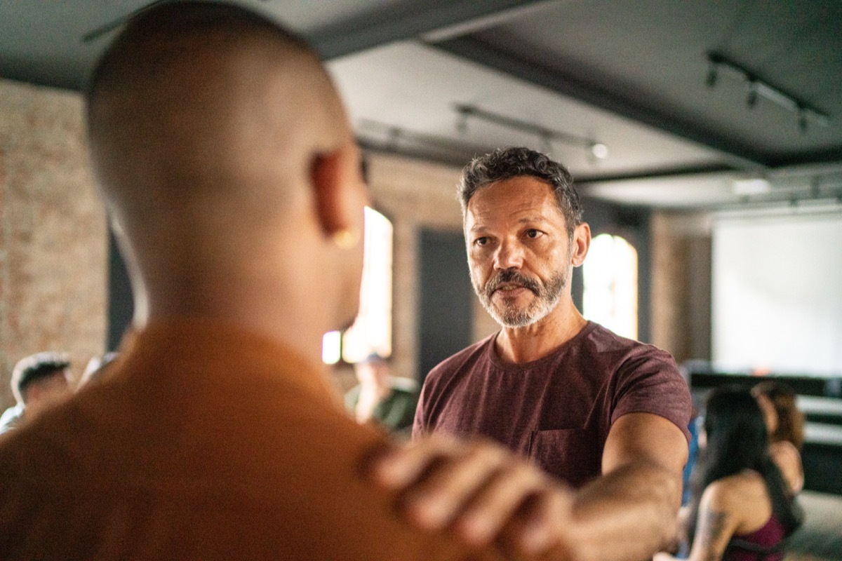 Mature man giving support to a young man during a psychotherapy session