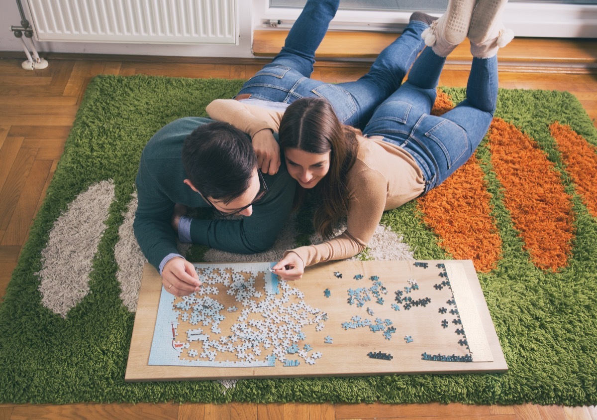 young white couple doing jigsaw puzzle on floor