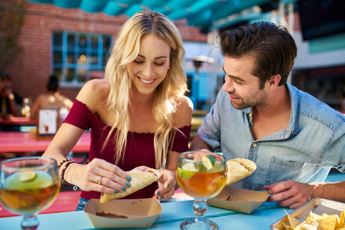 couple sharing tacos at an outdoor restaurant