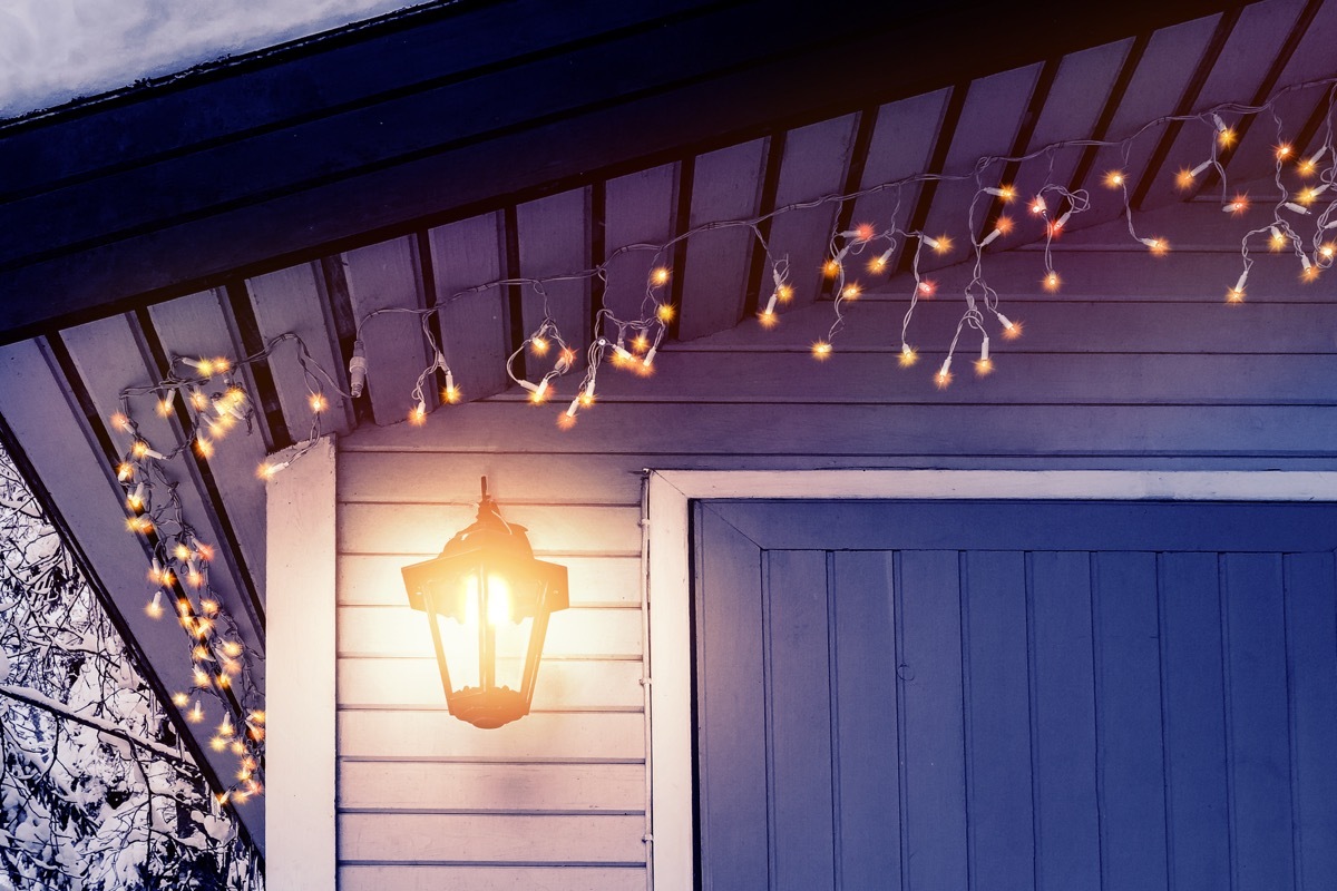 Porch of the house is decorated in the traditional Scandinavian style with a lantern and Christmas lights - concept of home warmth, comfort, family holiday.