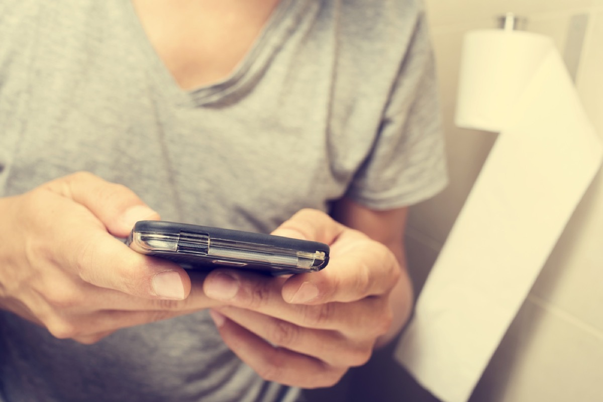 woman in gray shirt on her phone in the bathroom, rude behavior