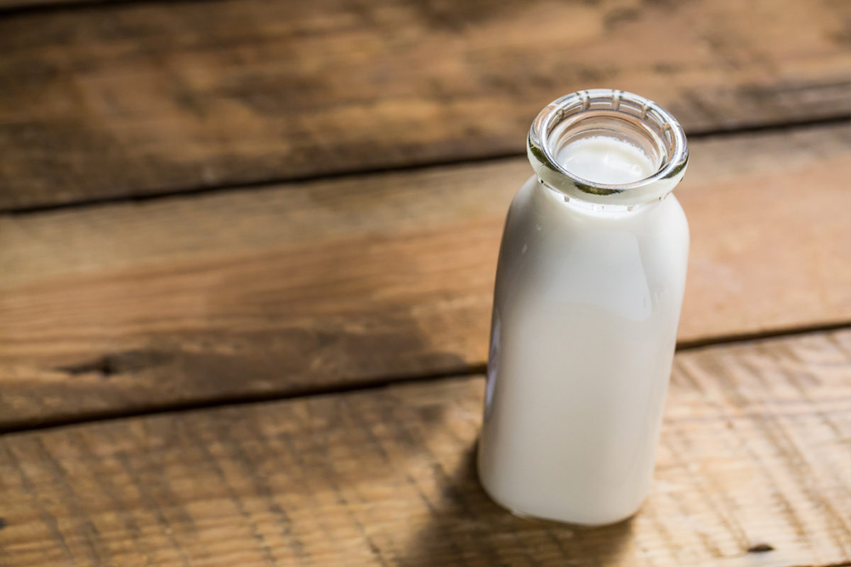 Old style bottle of milk sitting on wood table shot from slightly above with selective focus.