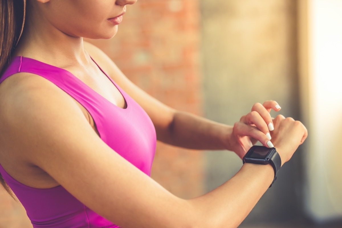 an athletic woman checks her fitbit