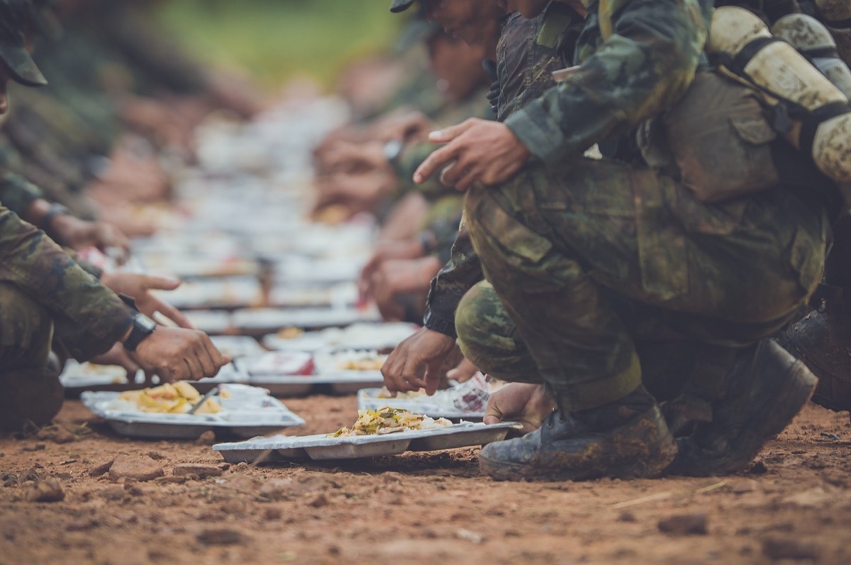 soldier arms reached out and legs bent down as they eat food