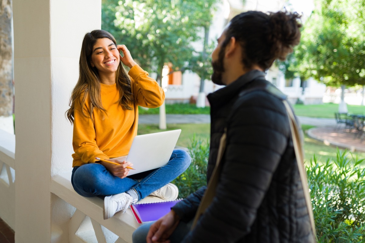 Beautiful young student flirting with a student while studying together on the college campus