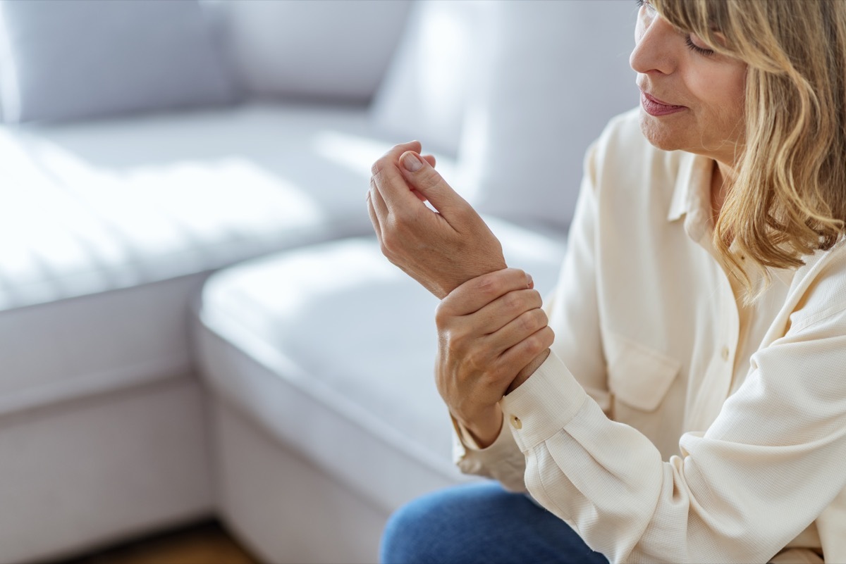 Senior woman suffering from pain in hand at home.