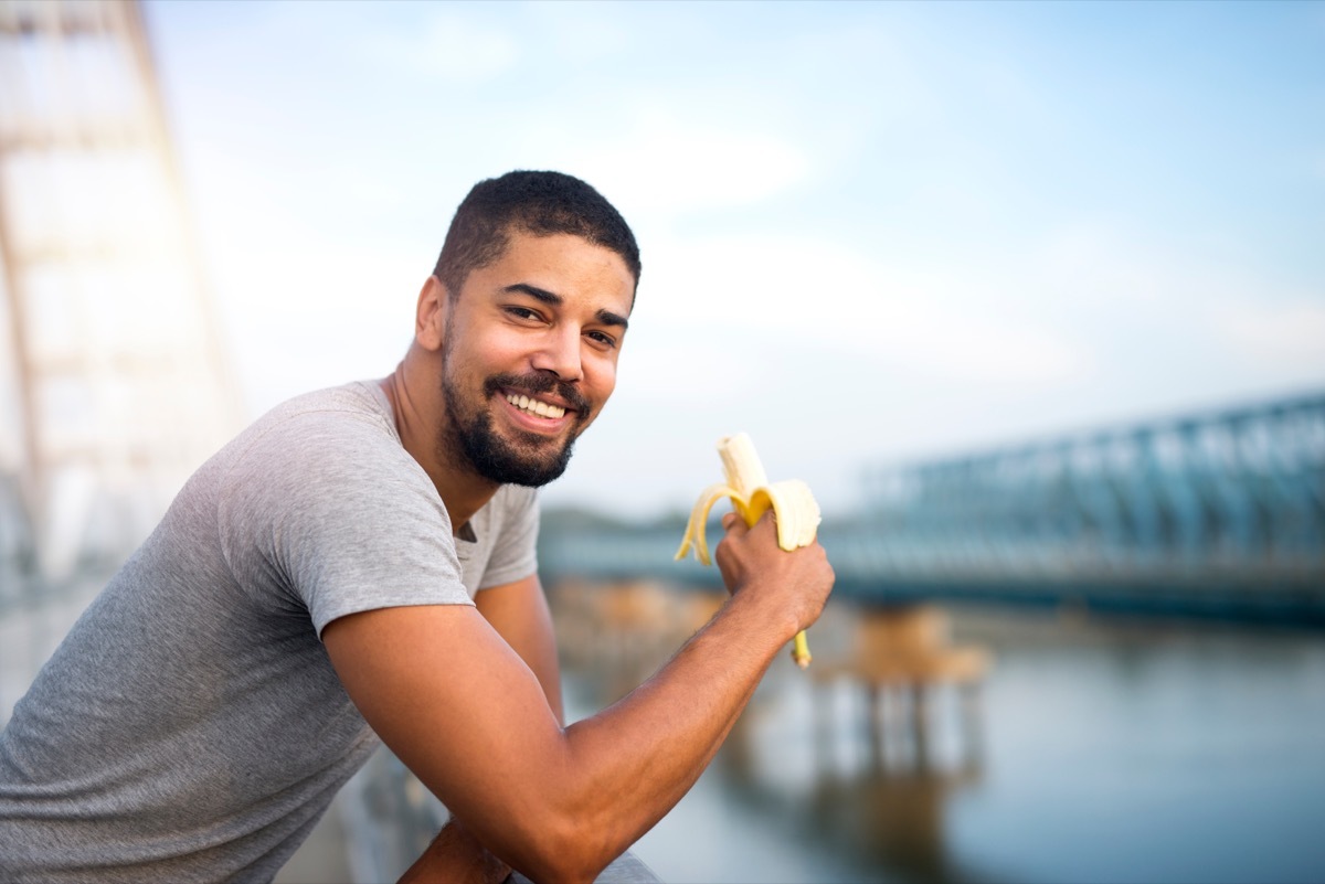 Black man eating a banana outside