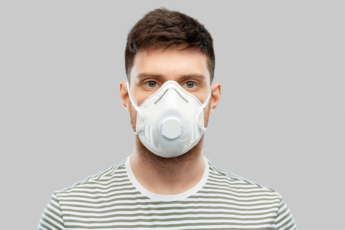 man in protective mask or respirator with valve over grey background 