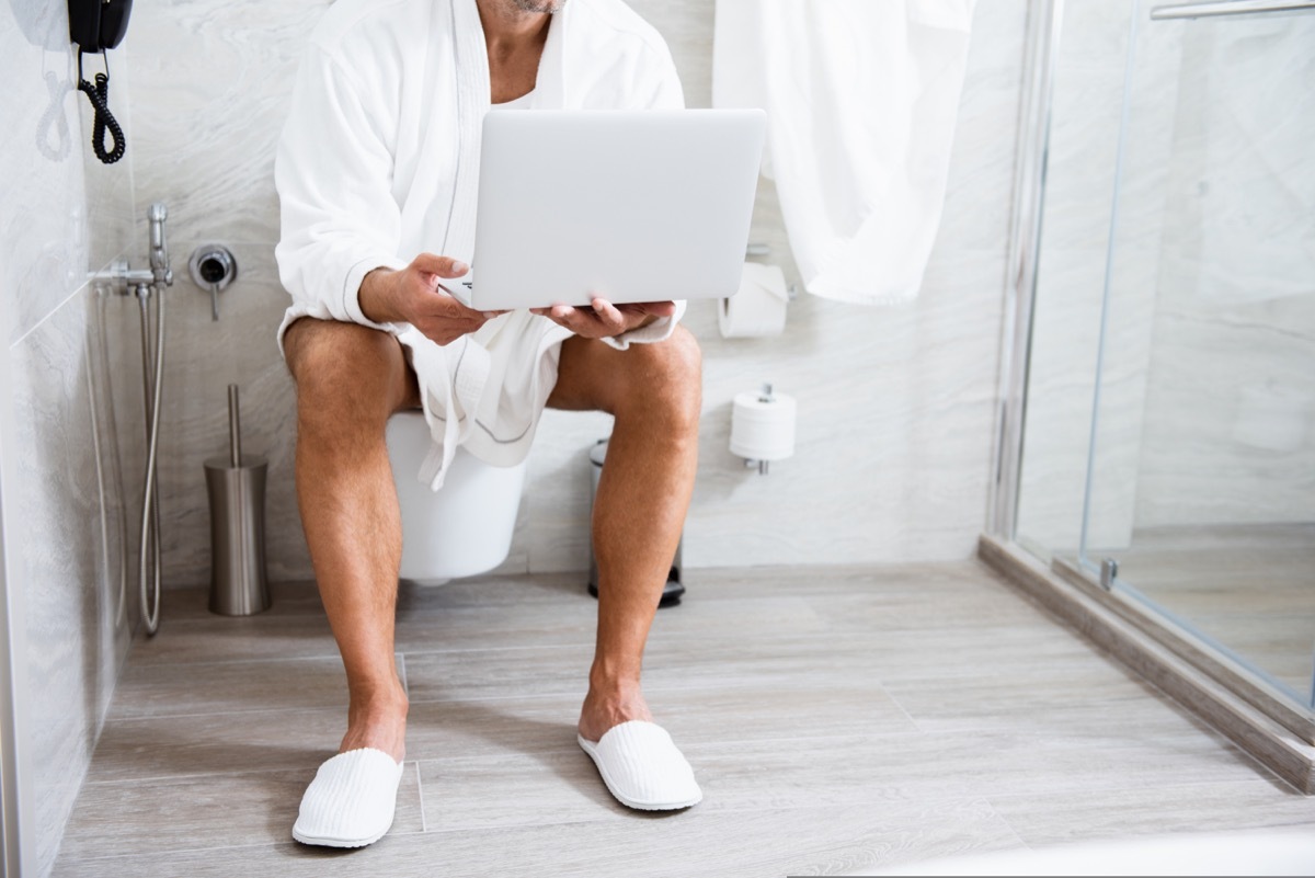 white man in robe taking call in the bathroom