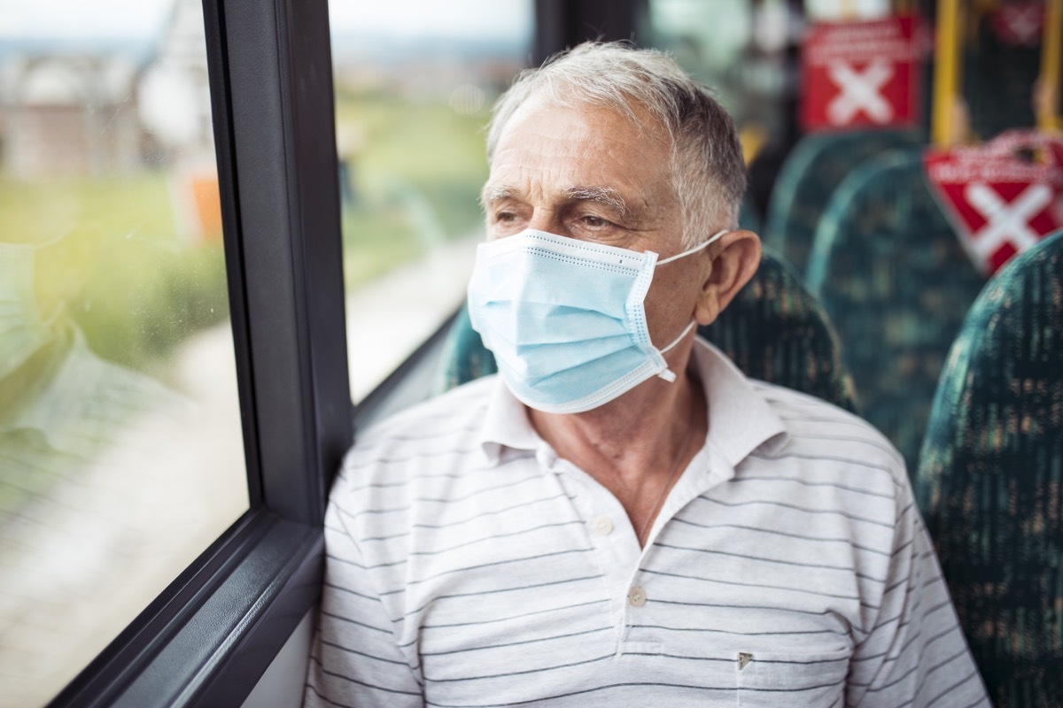 Senior man with respiratory mask traveling in the public transport by bus