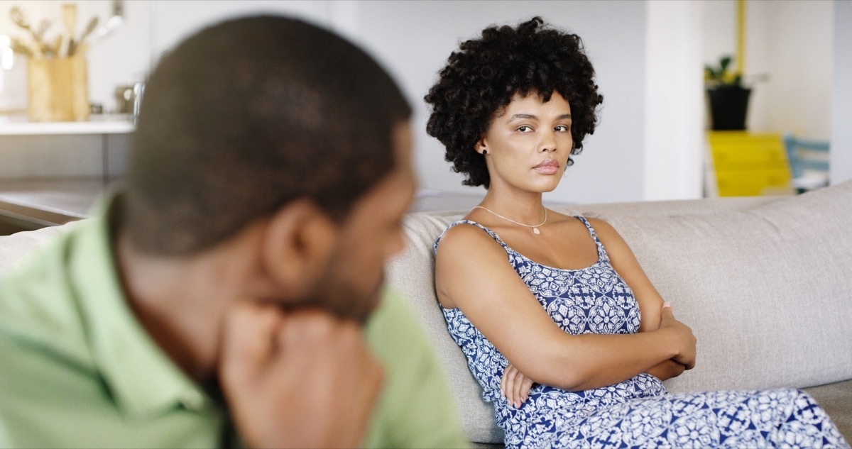 woman staring angrily at her partner while sitting on the couch