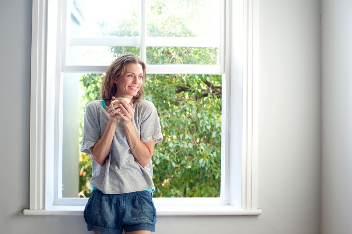 happy woman standing in front of open window