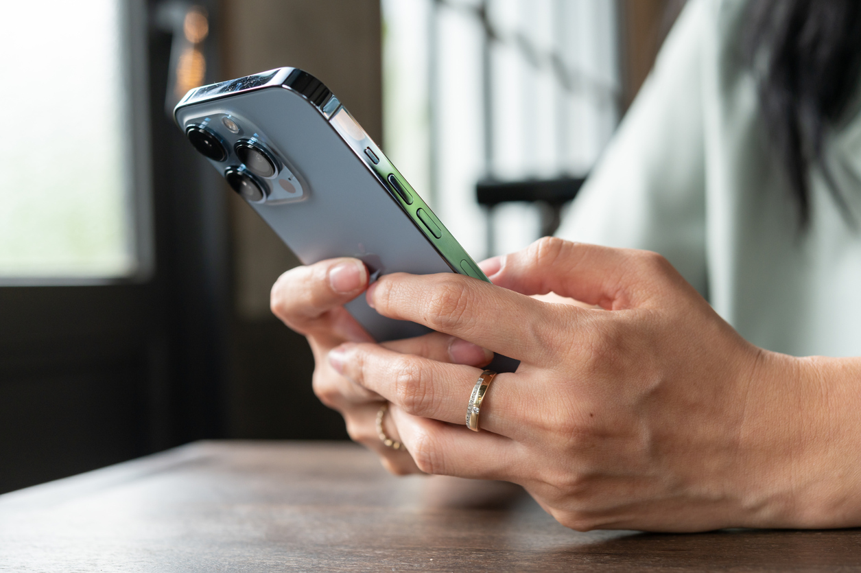 Close up of a person holding and using an iPhone