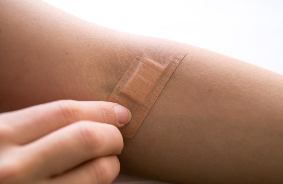 Woman removing adhesive plaster from the wound after blood test injection