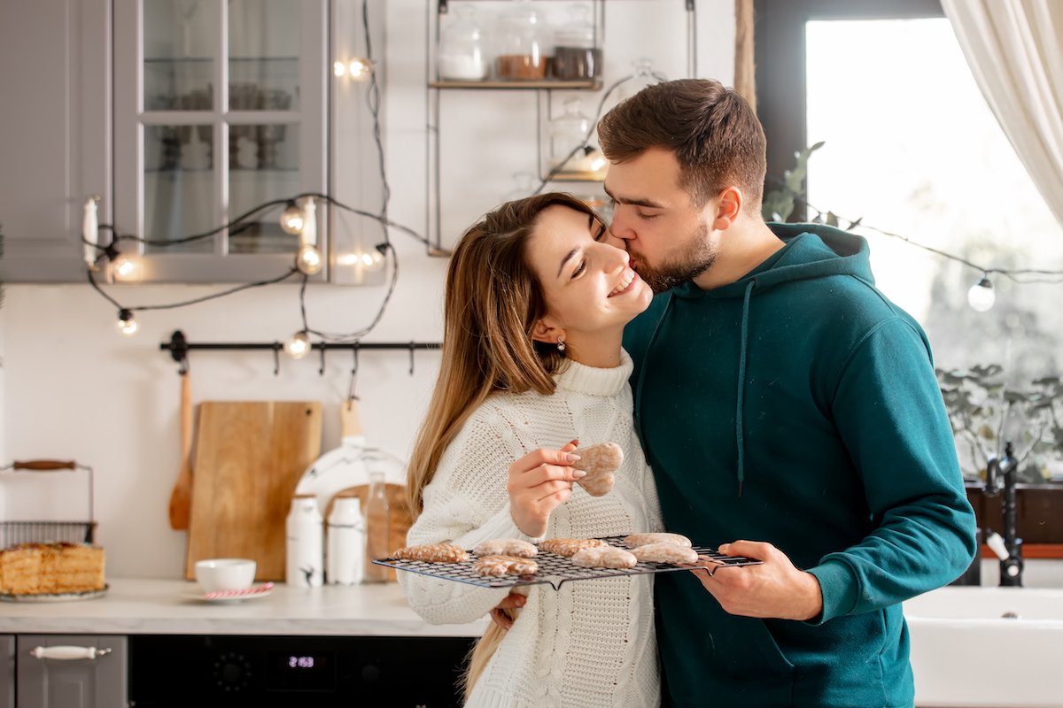 Young couple hugging while baking cookies in the kitchen