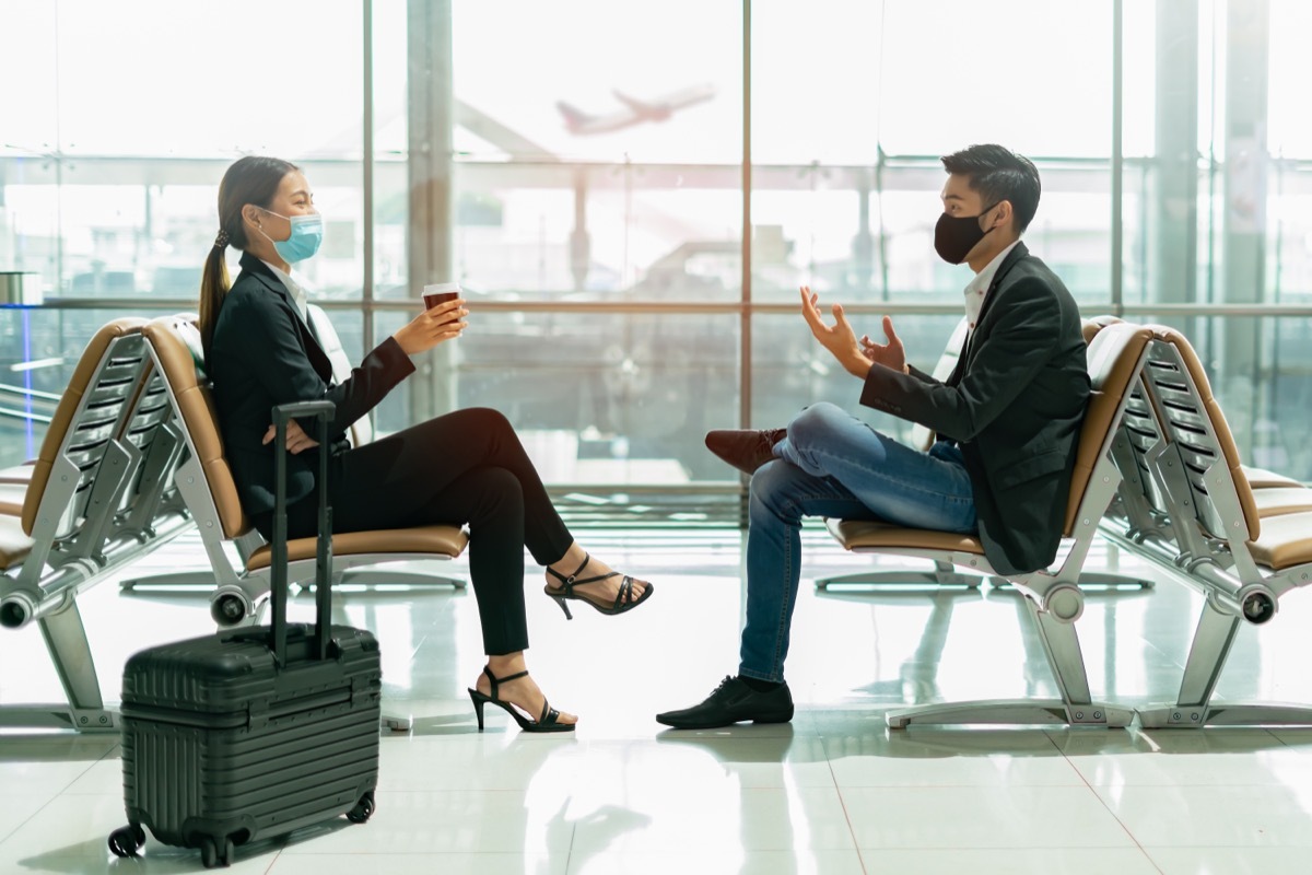 two co-workers social distancing while waiting for a flight