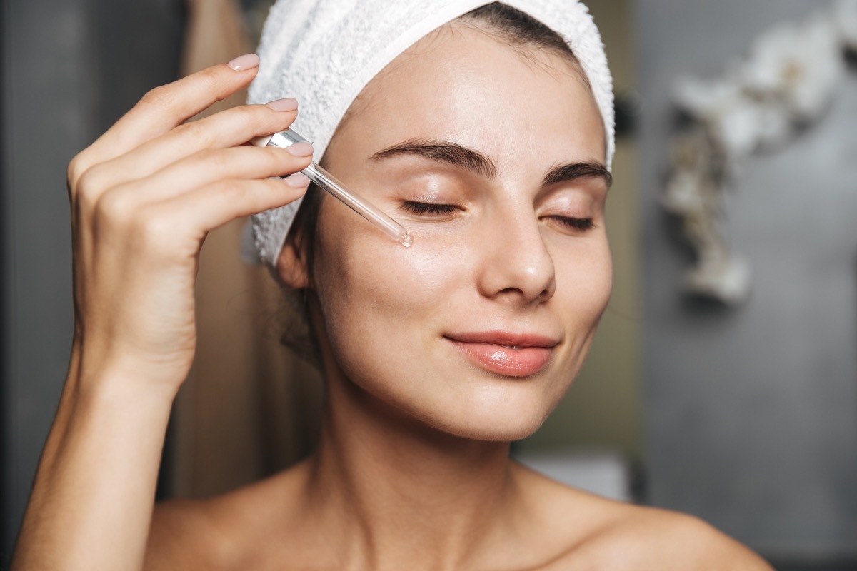 Woman applying oil to her face in bathroom