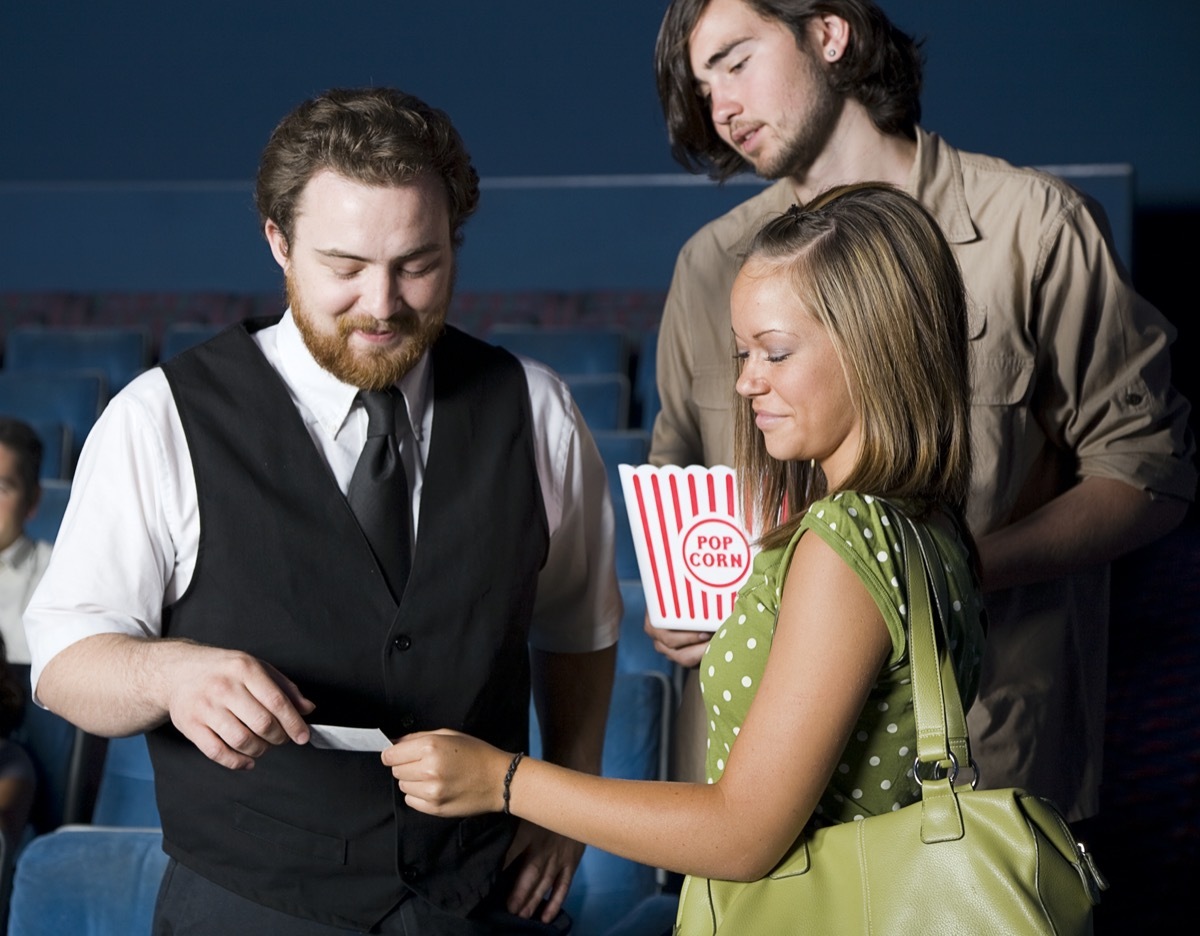 A young couple with an usher in a movie theater.