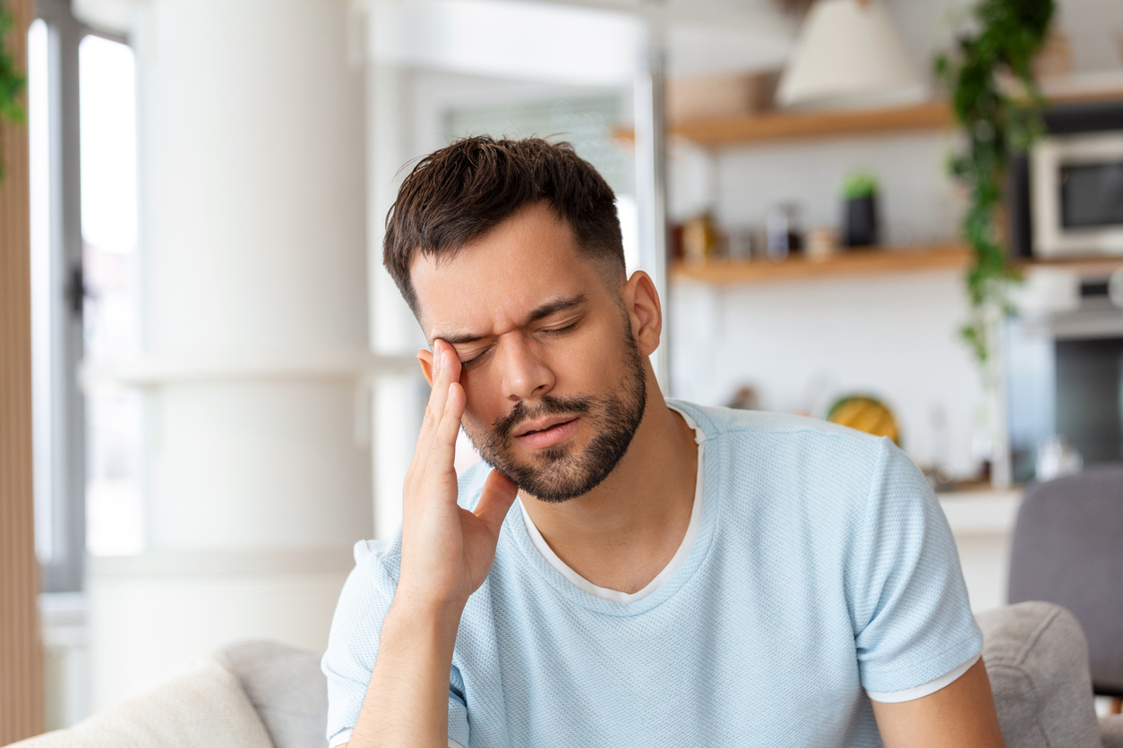 A man holding his head with his eyes closed suffering from a headache