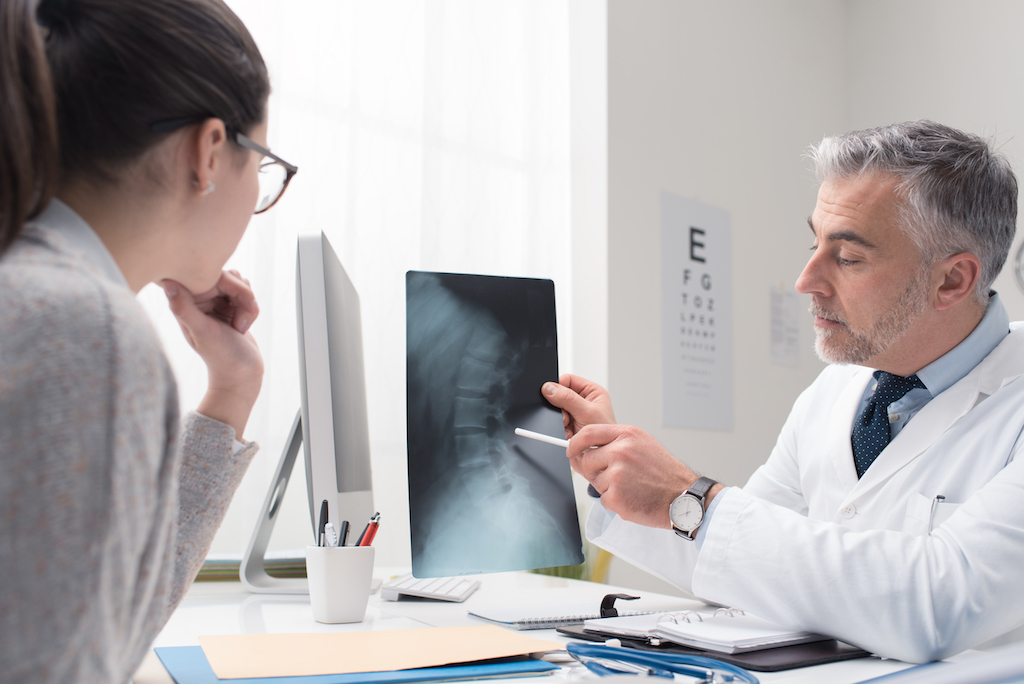 woman and doctor looking at an x ray of a spinal injury