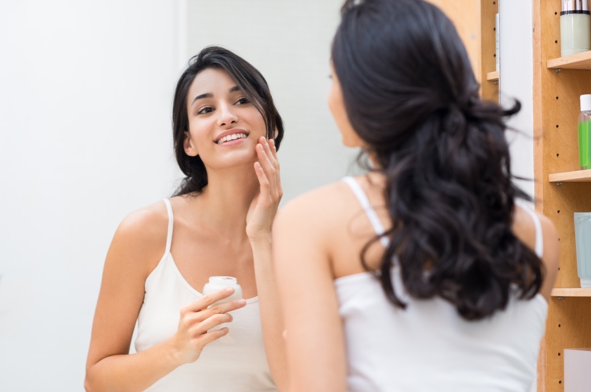 Woman moisturizing her face