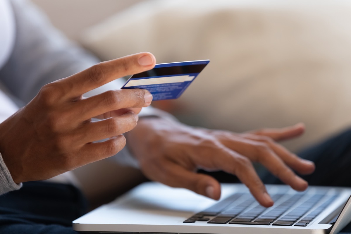 close up on hands holding credit card and typing on laptop