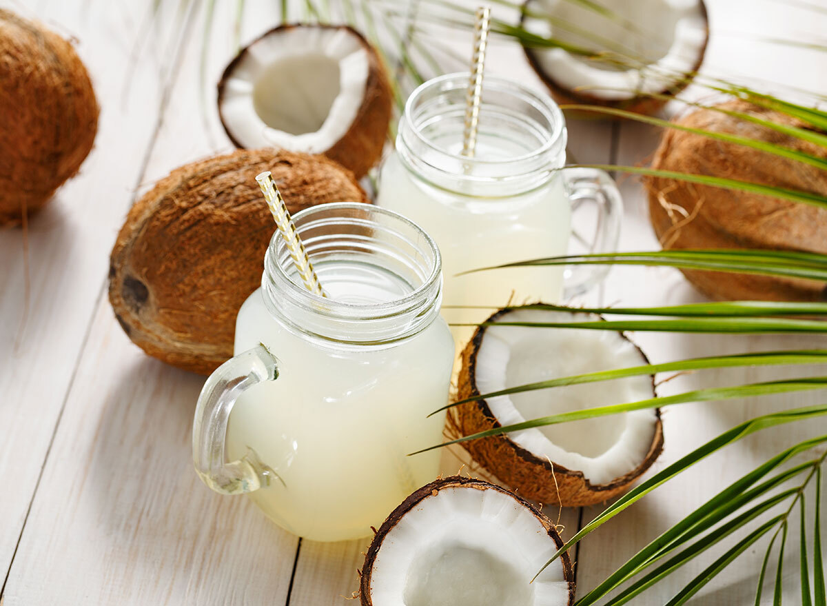 maron jar mugs filled with coconut water around coconuts