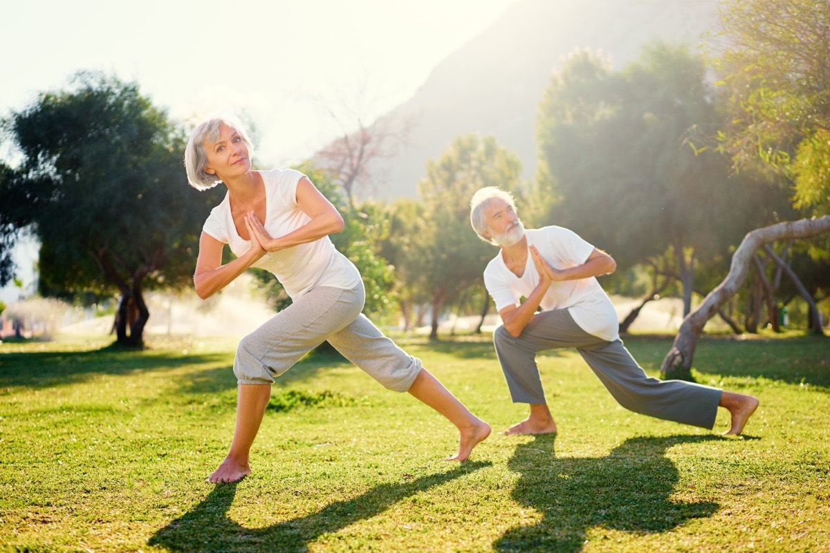 Yoga at park. Senior family couple exercising outdoors. Concept of healthy lifestyle.