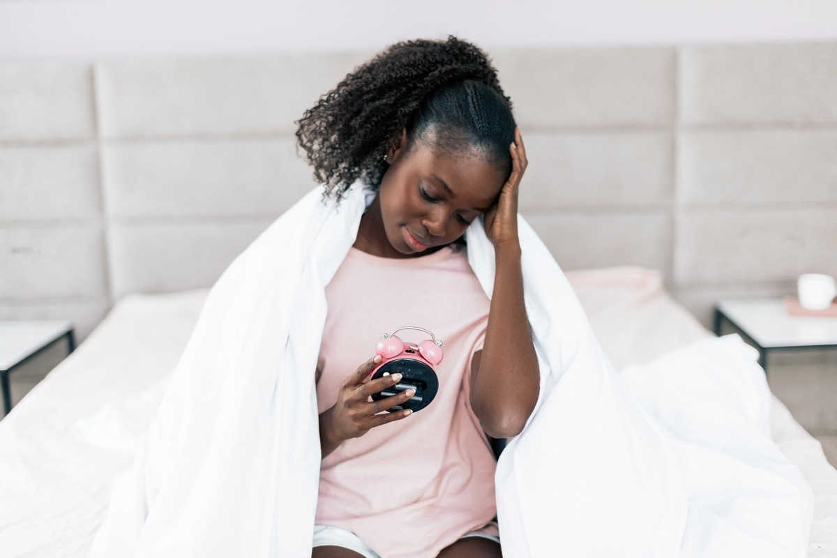 Tired Woman Holding Her Alarm Clock, signs you need a new mattress