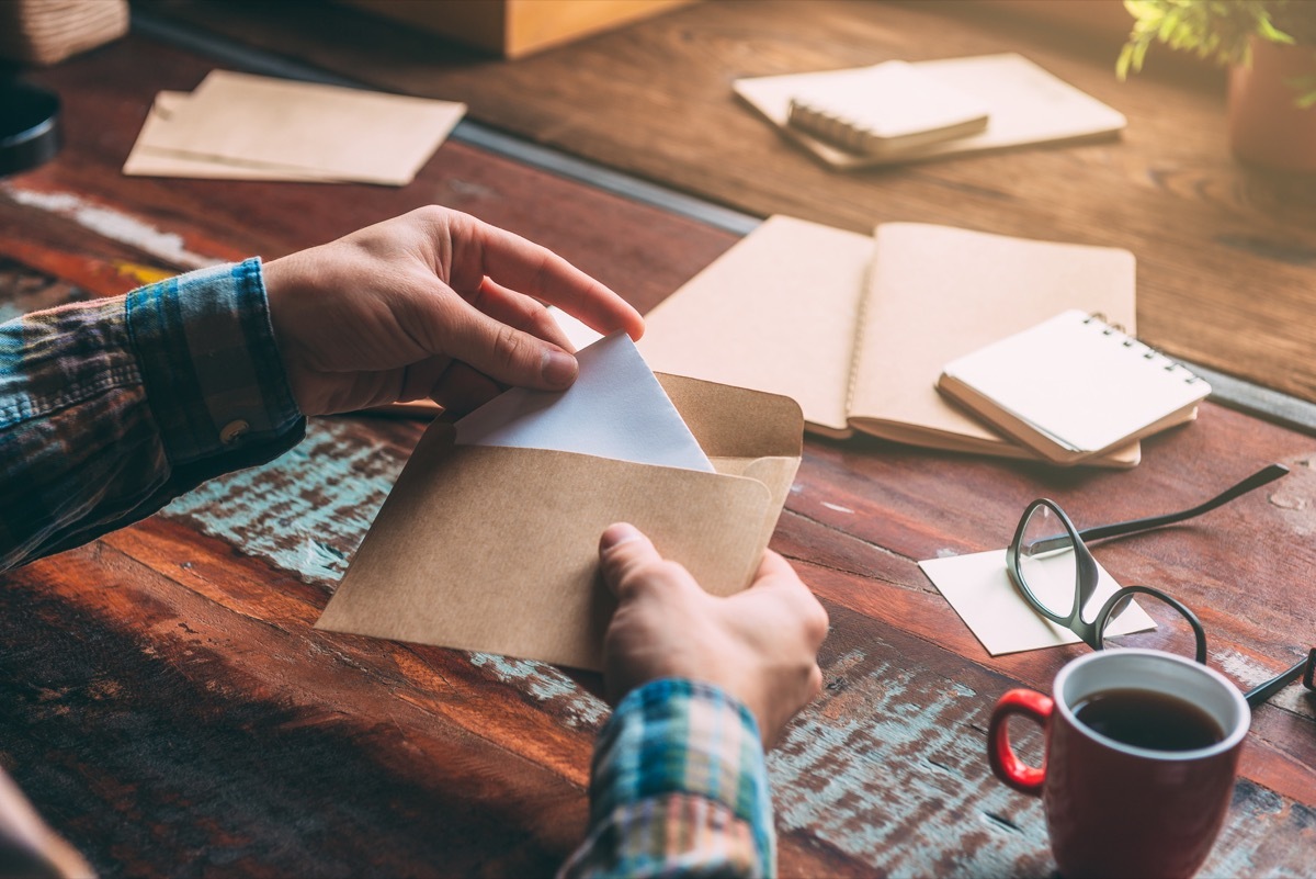 Person putting letter in an envelope to mail