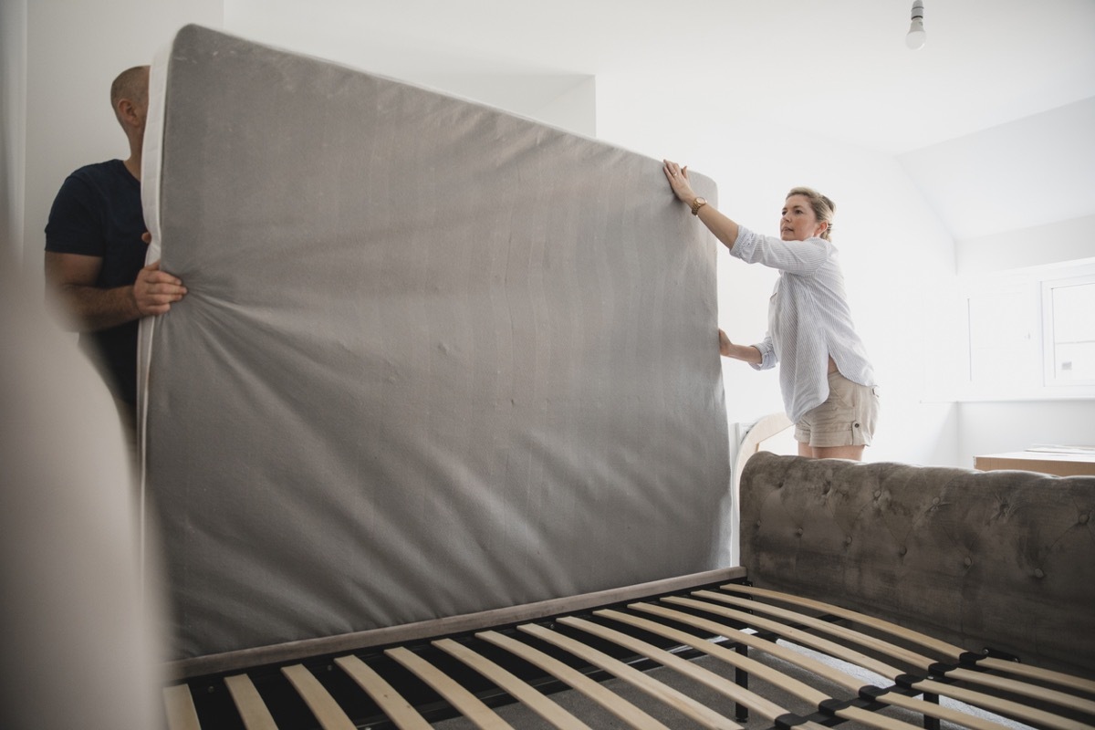 Mature couple are setting up their bed in their new home.