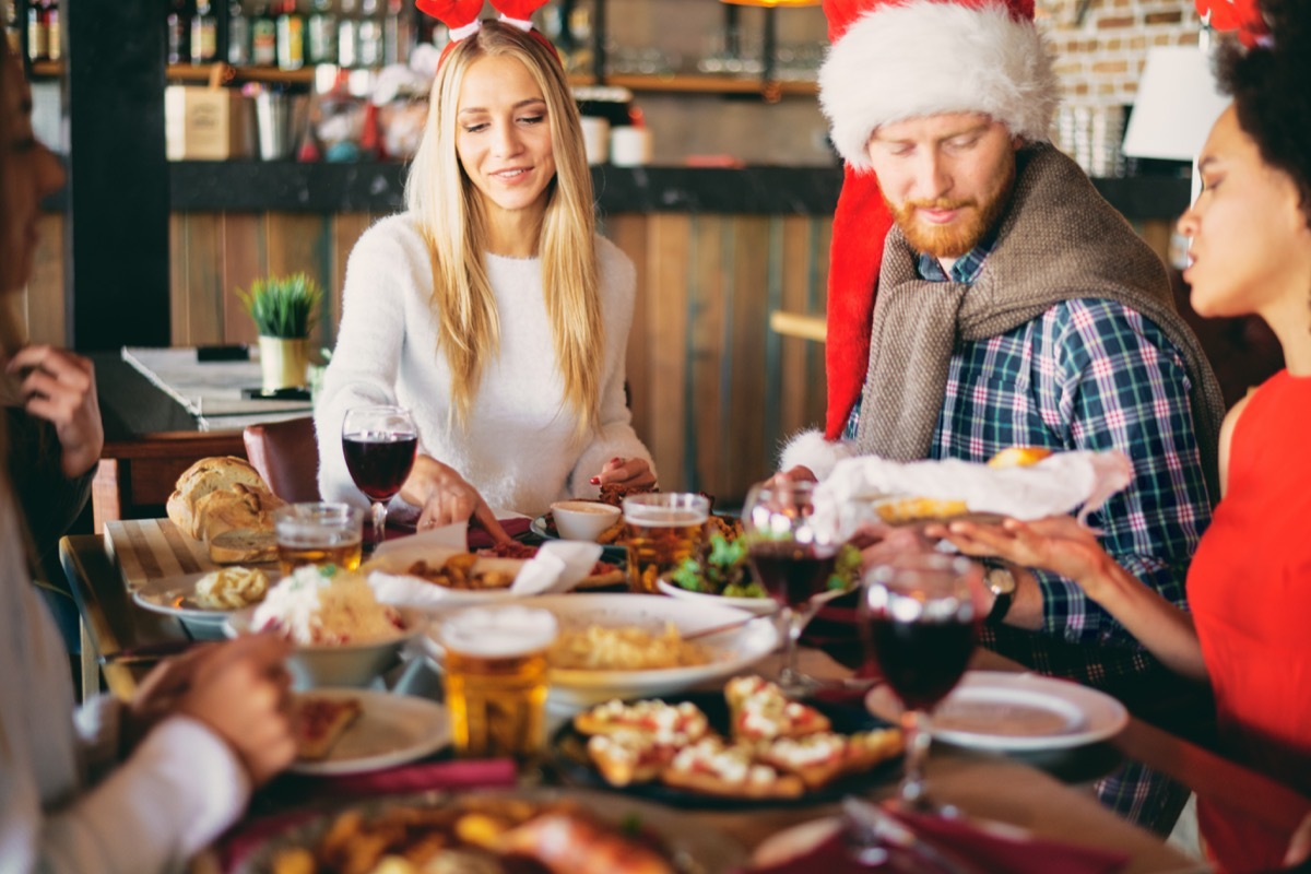 Friends having dinner on Christmas` eve at restaurant. Christmas holidays concept.