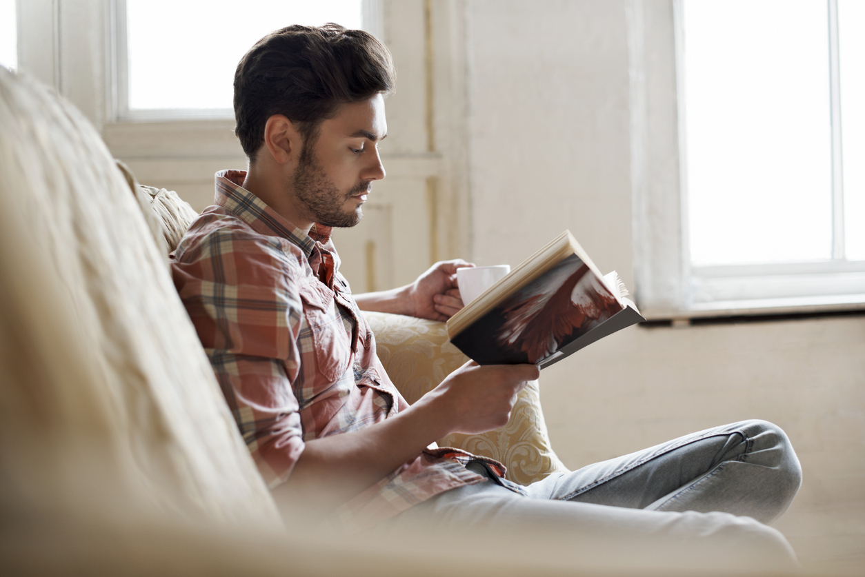 Man sitting on sofa reading a book