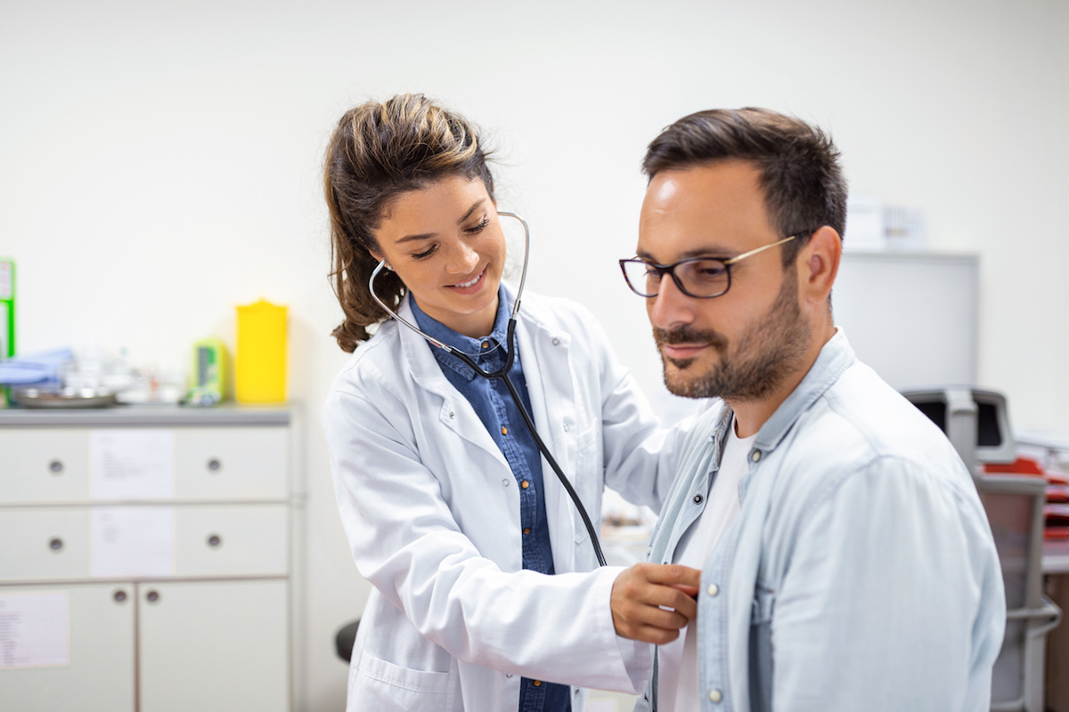 Young doctor is using a stethoscope listen to the heartbeat of the patient. Shot of a female doctor giving a male patient a check up