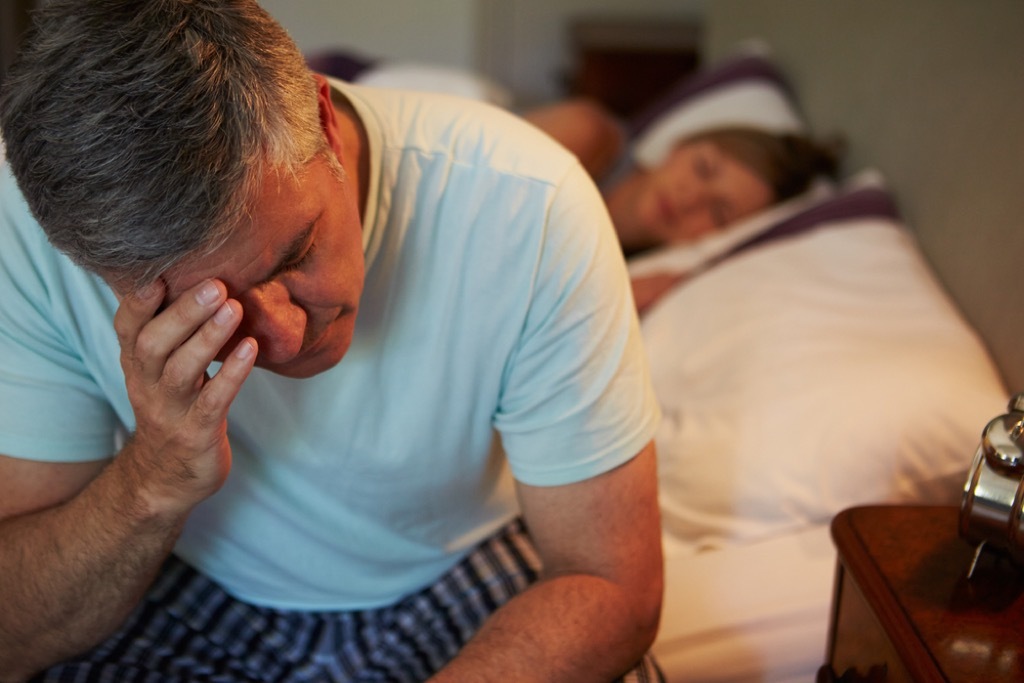 man awake in bed, signs of burnout