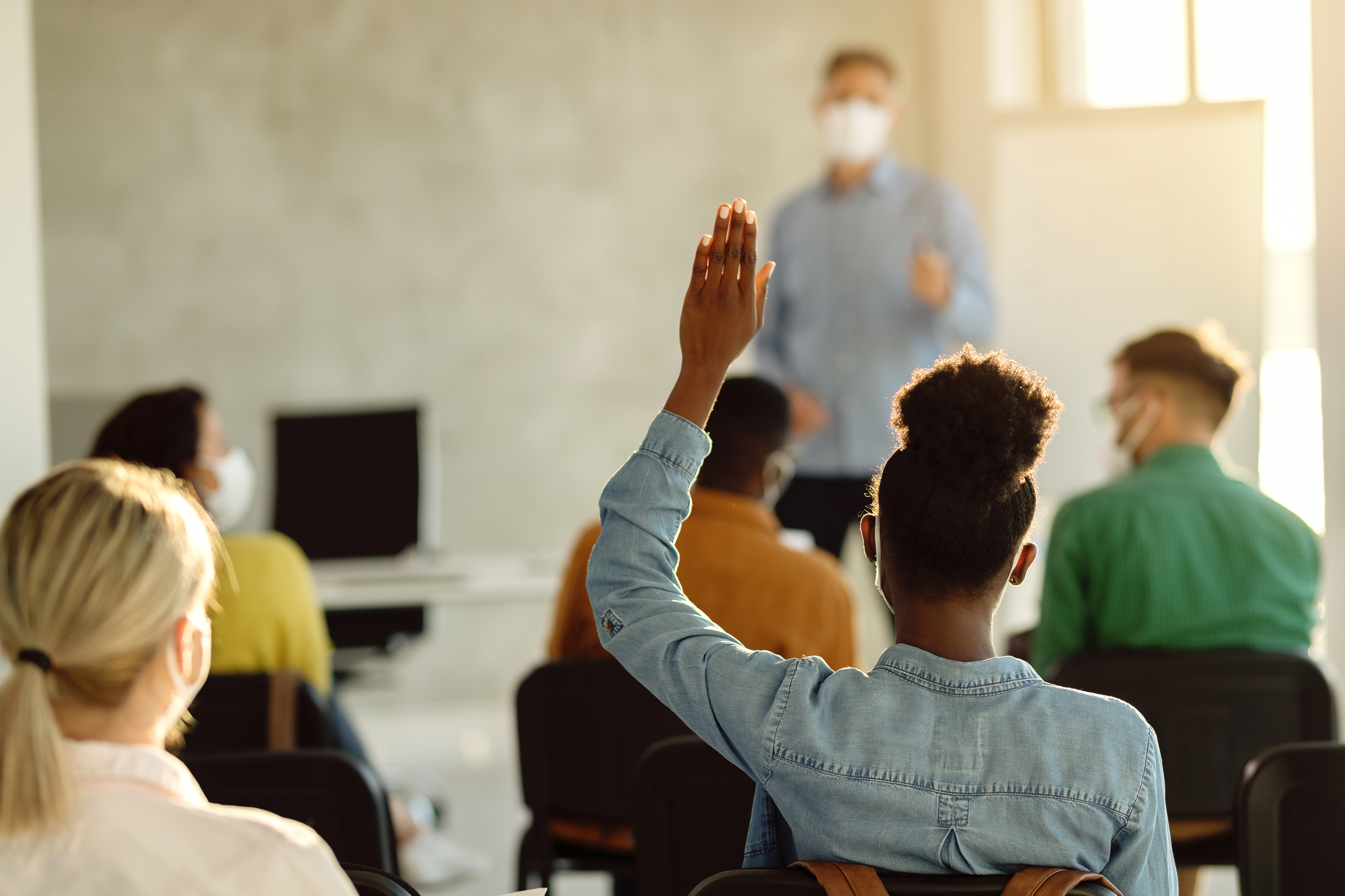 student raising her hand in a classroom