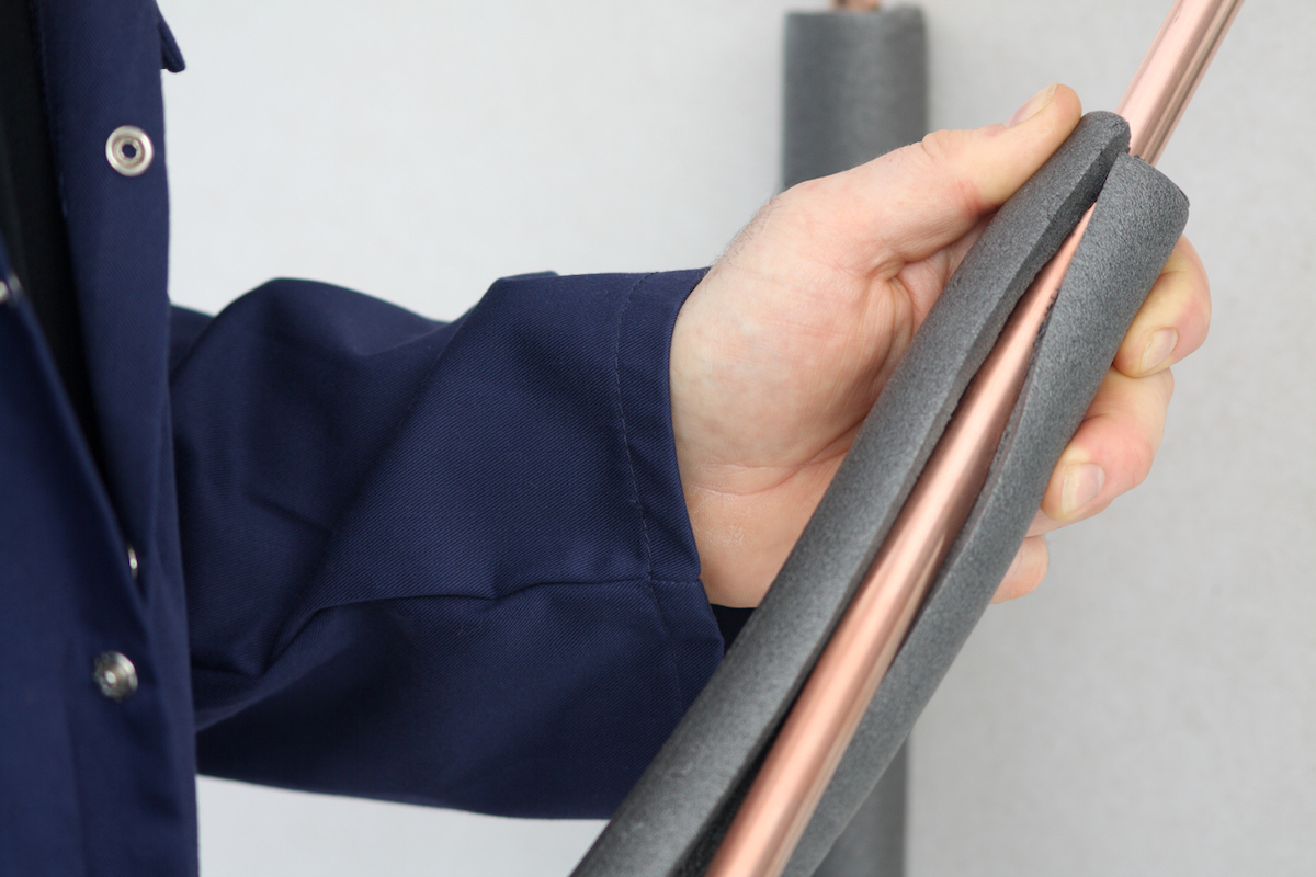 Plumber applying insulation to a water pipe.