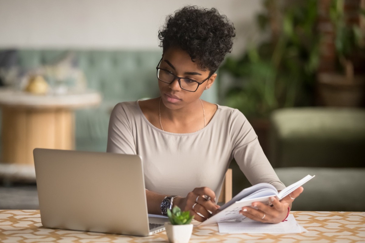 Focused Young Woman with Laptop and Notebook