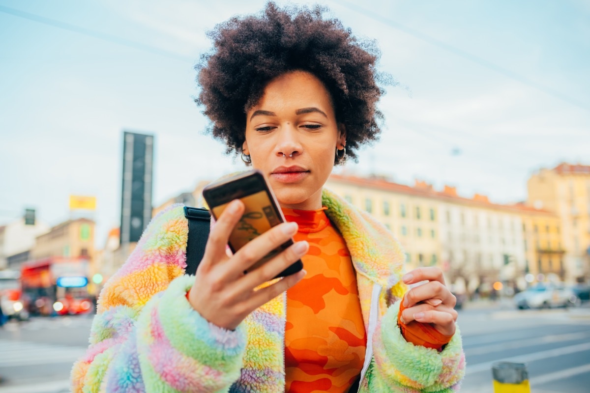 woman walking outside while reading a text message